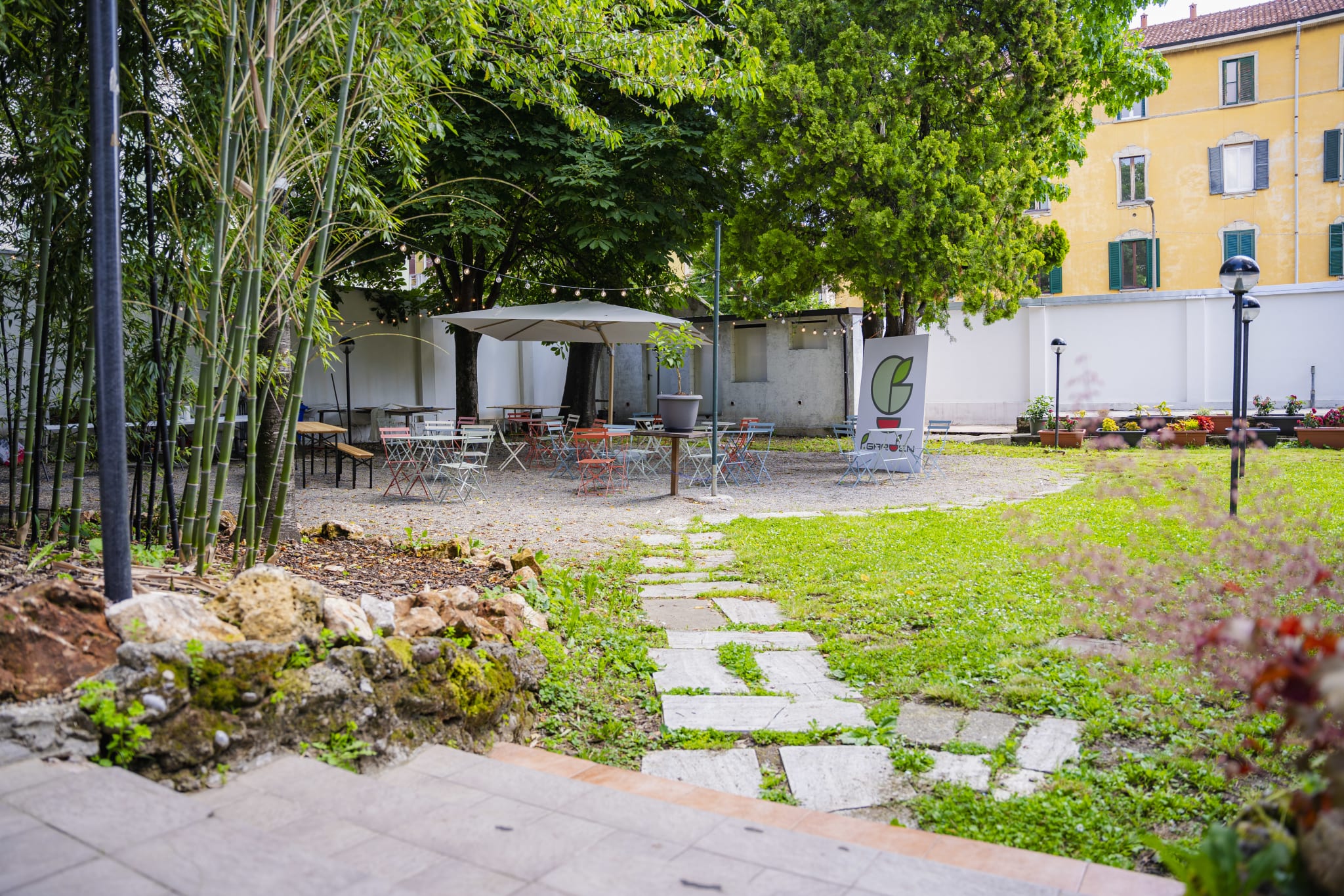 Il giardino del P.Garden Monza con tavolini, alberi e ombrelloni